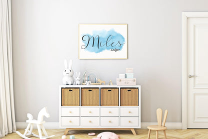 Custom nursery name sign with Miles Ledger in script on blue watercolor background, displayed above nursery storage, perfect as a personalized baby gift.