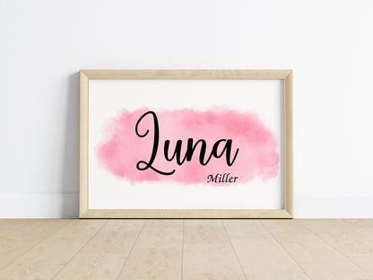 Custom baby name sign reading Luna Miller in script on pink watercolor background, minimalist nursery decor and unique baby shower gift idea.