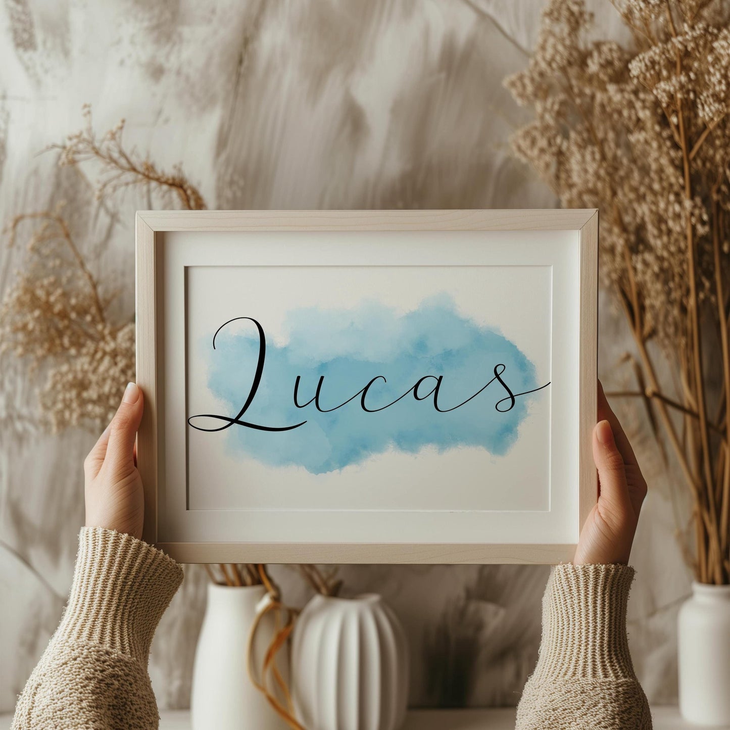 Framed baby name sign with Lucas in script over blue watercolor background, held in hands, perfect custom nursery decor and baby gift.