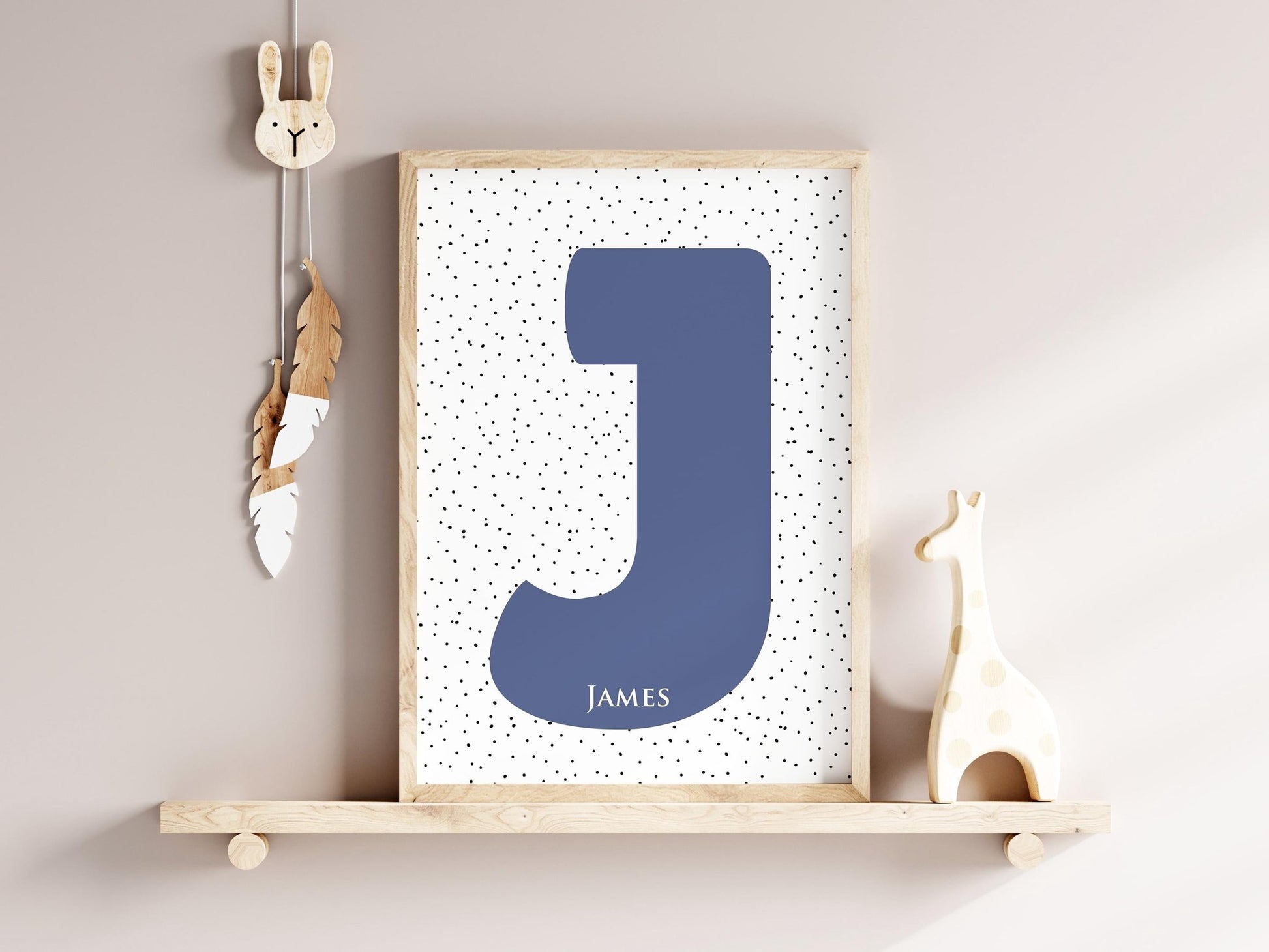 Custom initial name sign with large navy letter J and dotted background on a nursery shelf, decorated with a giraffe and bunny