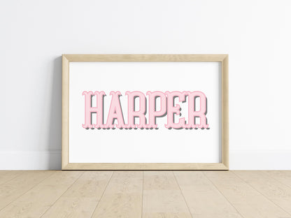 Pink custom baby name sign in a simple frame on wooden flooring, perfect as a personalized addition to nursery decor or as a new baby gift.