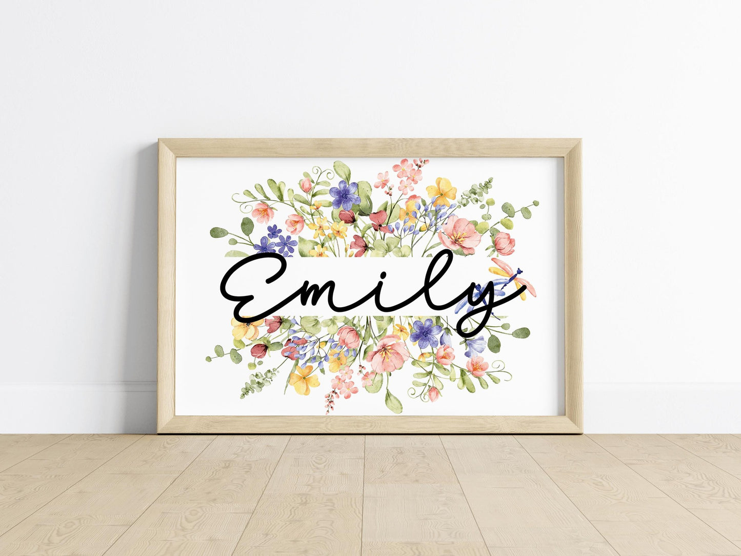 Hands holding a framed wildflower name sign with customizable text and intricate floral patterns, highlighting its charm as a personalized baby gift.