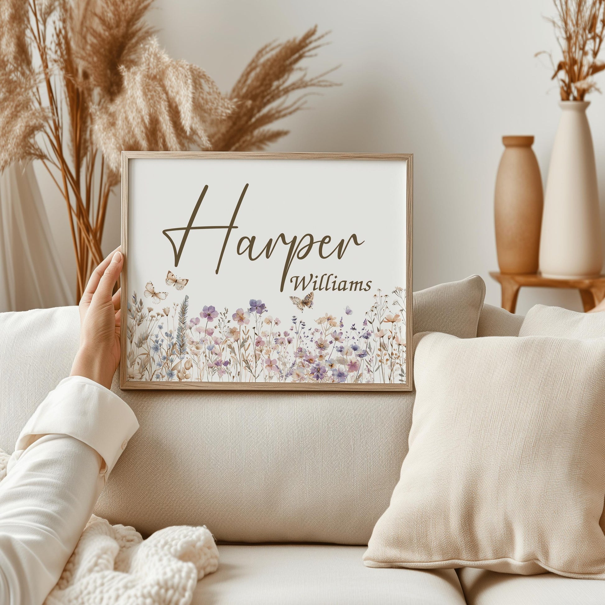 Hand-held custom wildflower name sign in a cozy living room, ideal for floral nursery decor or a thoughtful baby shower gift.