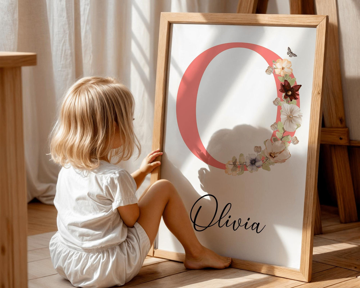 Charming nursery name print with a pink initial and wildflower accents, suitable for above crib decor and personalized girl nursery themes.