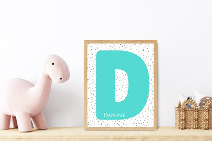 Personalized turquoise initial name sign with letter D and dotted background, perfect for a baby’s room or nursery decor with a soft dinosaur toy