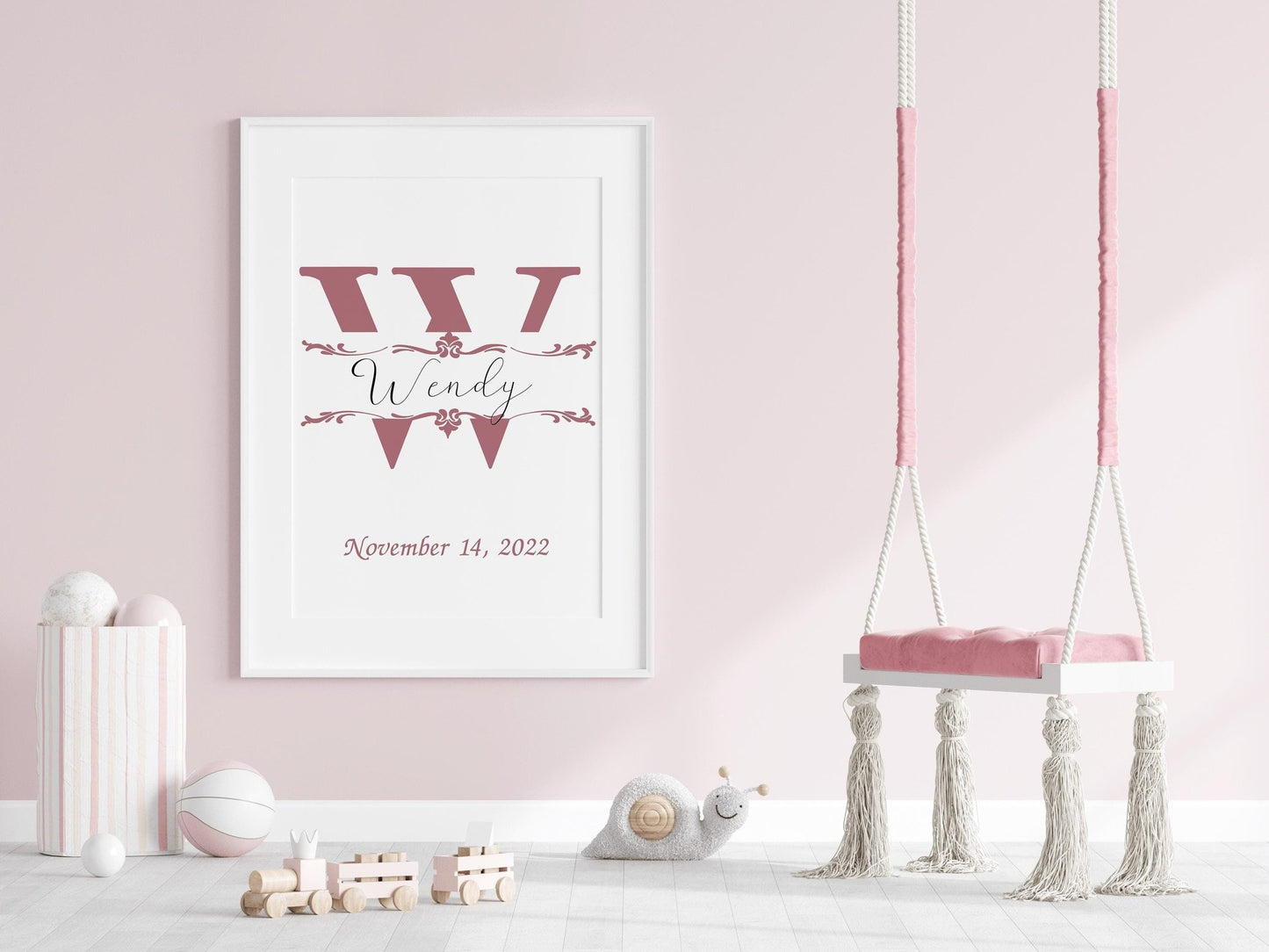 Custom baby name sign with a large pink initial and elegant font displayed in a pastel pink nursery, ideal for nursery wall art or baby gifts.