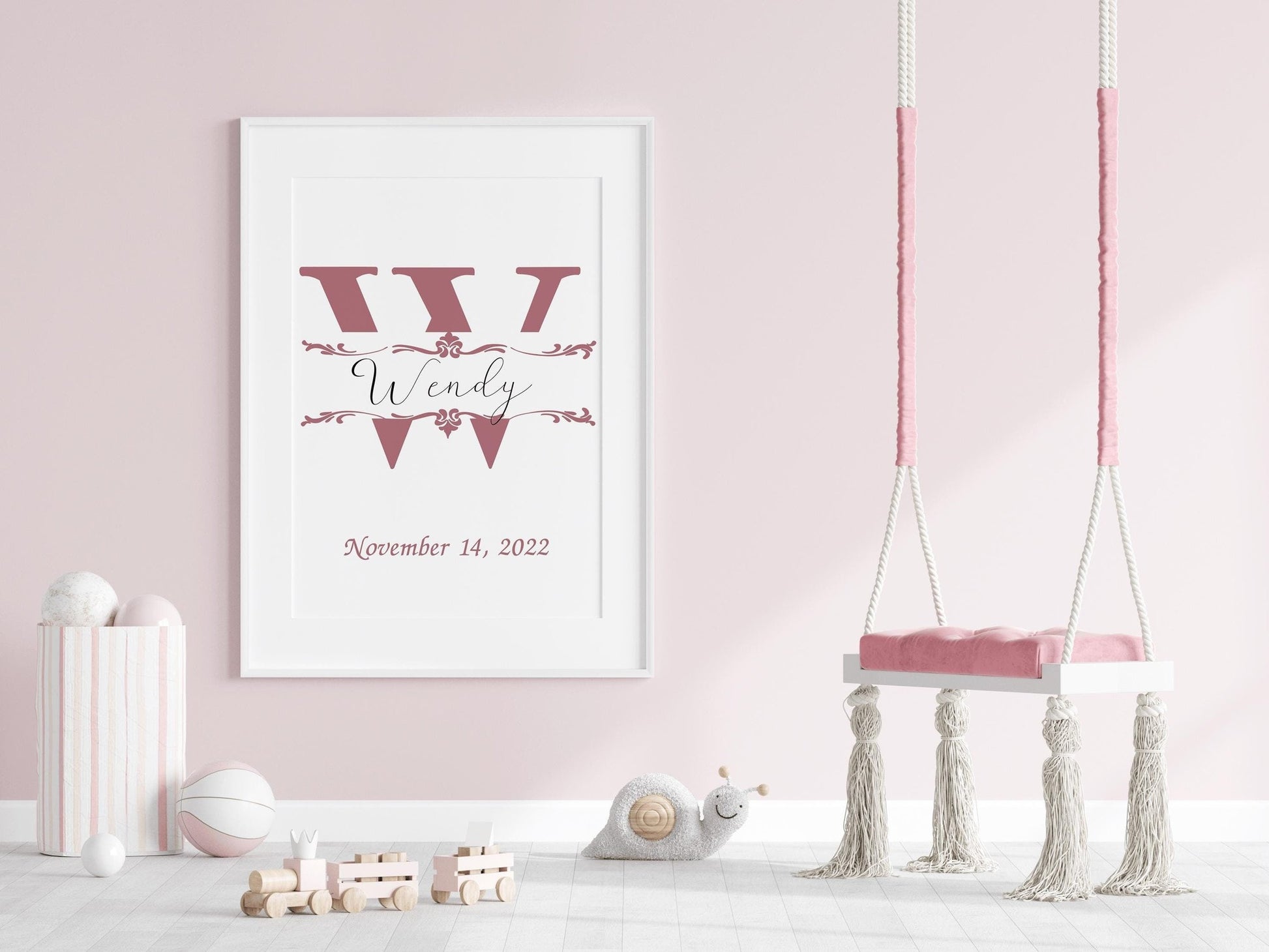 Custom baby name sign with a large pink initial and elegant font displayed in a pastel pink nursery, ideal for nursery wall art or baby gifts.