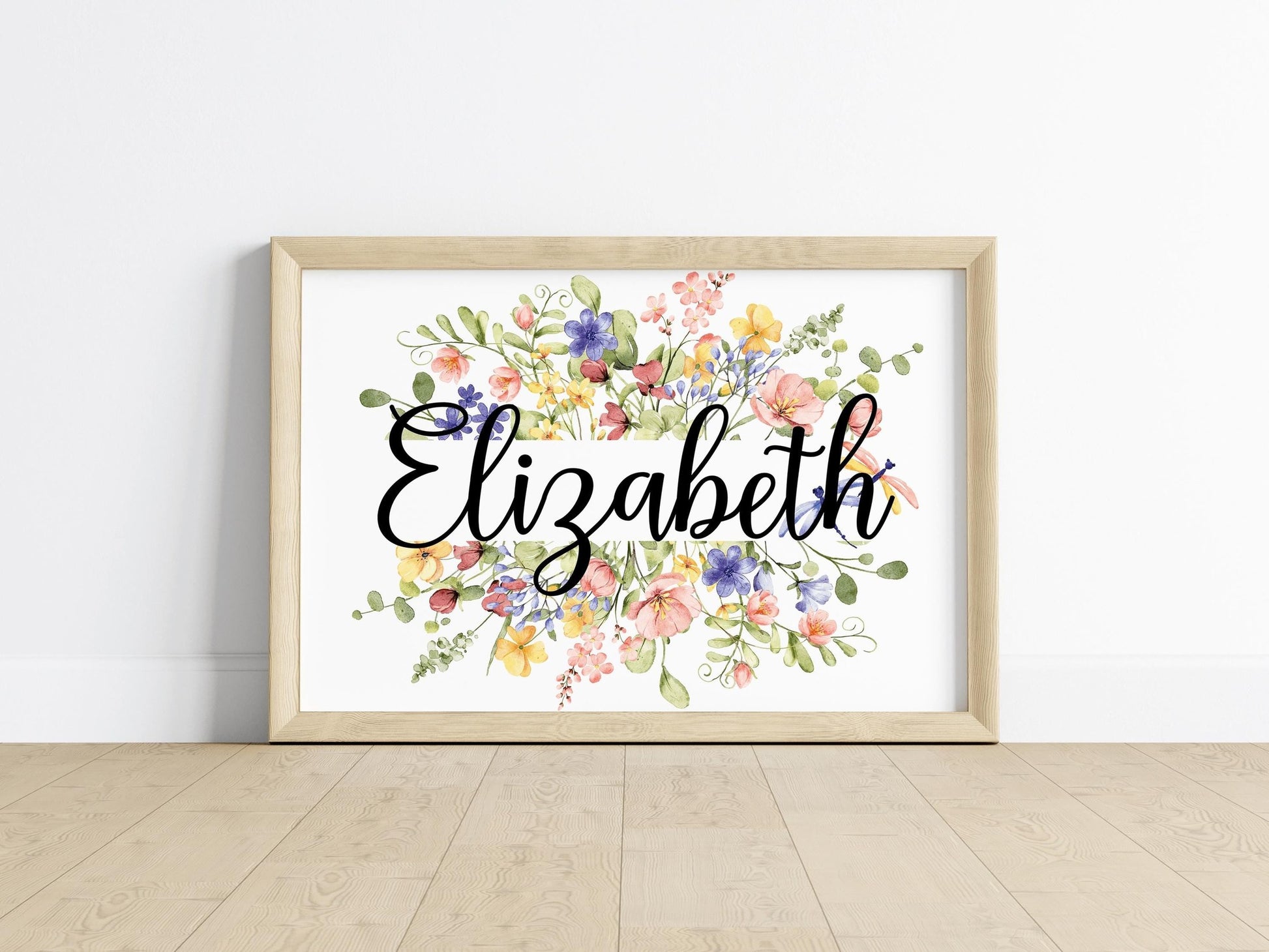 A framed floral name sign featuring delicate wildflowers, perfect for custom nursery decorations and unique baby shower gifts.