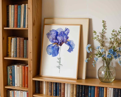 Modern bedroom with a framed blue iris flower artwork personalized with the name Emily being held by a seated woman perfect for serene home interiors.